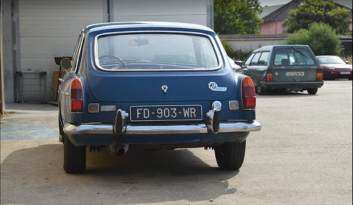 Vue arrière d'une voiture bleue vintage (MG B GT) garée devant un garageautomobile à Gargenville près de Mantes-la-Jolie dans les Yvelines 78