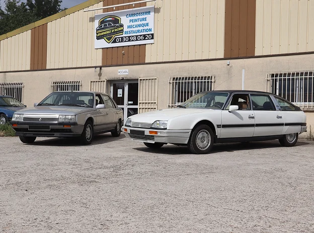 Deux voitures classiques, une Citroën CX et une Renault 25, garées devant un garage à Gargenville près de Mantes-la-Jolie dans les Yvelines 78