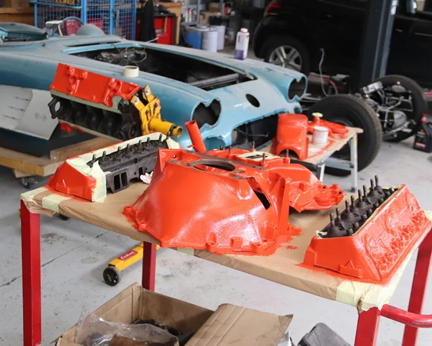 Pièces de moteur de voiture orange vives sur une table dans un garage à Gargenville près de Mantes‑la‑Jolie dans les Yvelines 78