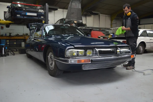 mécanicien essuie une voiture bleue classique dans un garage à Gargenville près de Mantes‑la‑Jolie dans les Yvelines 78