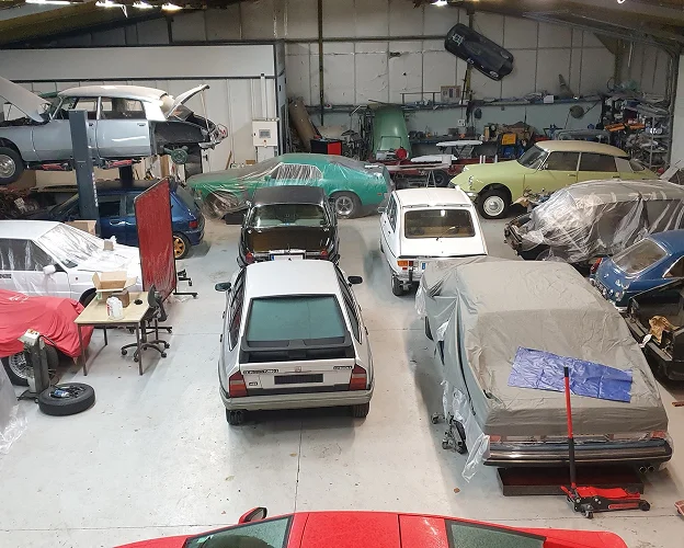 Un garage rempli de voitures classiques françaises, dont plusieurs Citroën et une Renault à Gargenville près de Mantes-la-Jolie dans les Yvelines 78